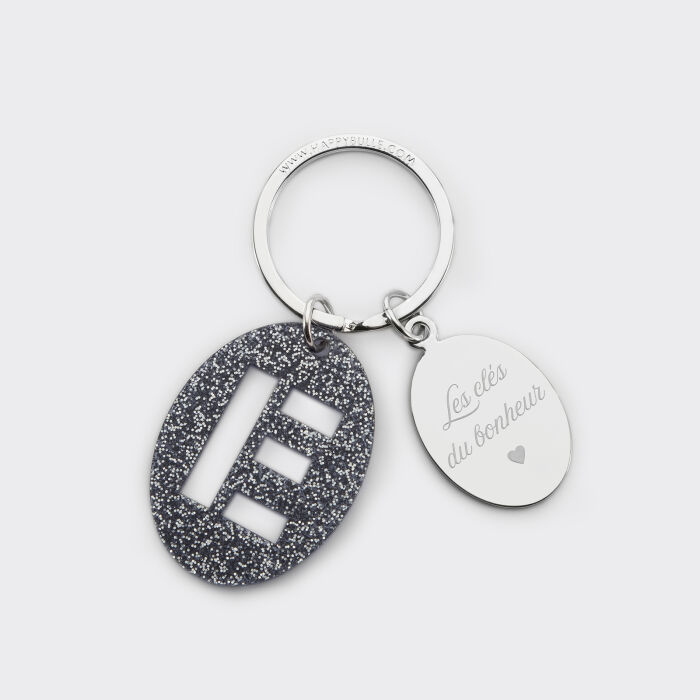Porte-clés personnalisé médaille gravée ovale acier et breloque initiale acrylique pailleté bleu nuit texte manuscrit