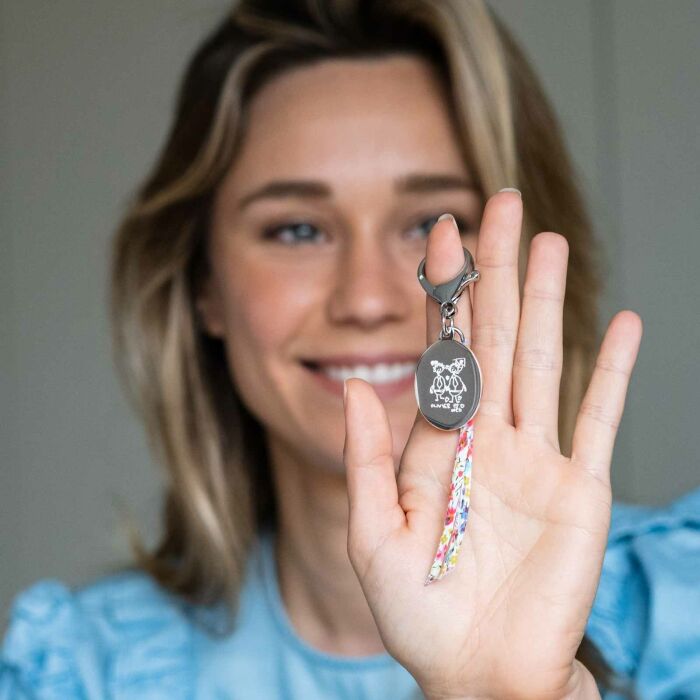 Bijou de sac personnalisé médaille gravée acier ovale 33x25 mm et noeud Liberty - main ambiance