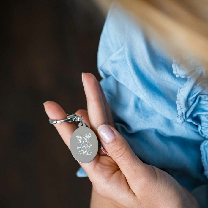 Bijou de sac personnalisé médaille gravée acier ovale 33x25 mm et noeud Liberty - main